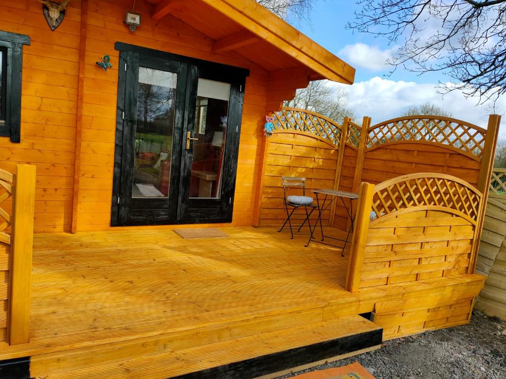 Cabaña con terraza de madera y silla en ANNES LOG CABIN en Nobber