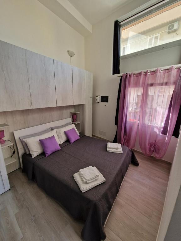 a bedroom with a large bed with purple pillows at LA CASETTA in Cagliari