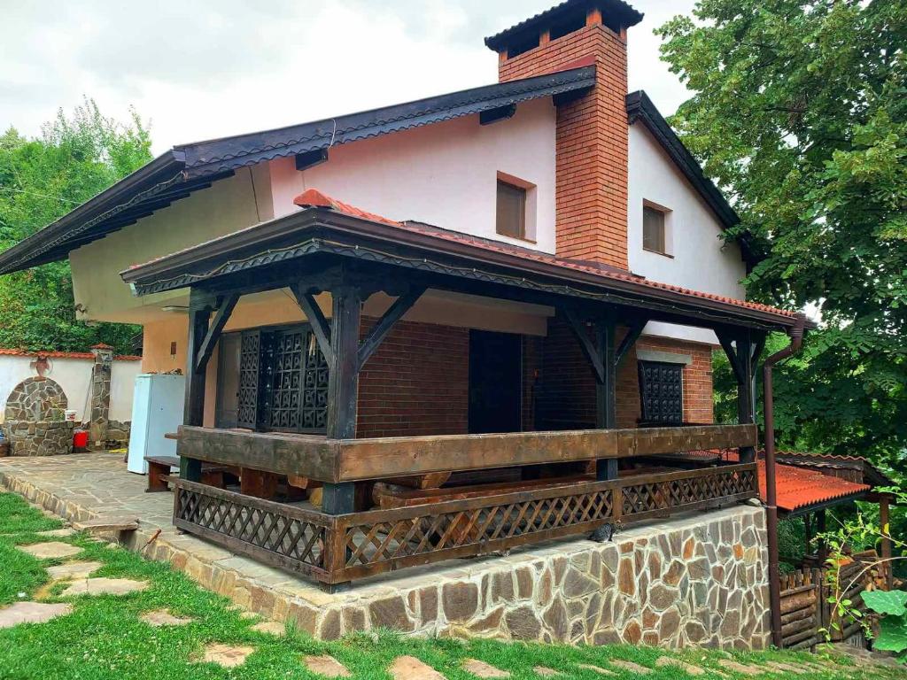 ein kleines Haus mit einer Veranda an einer Steinmauer in der Unterkunft Къща за гости Диляна 