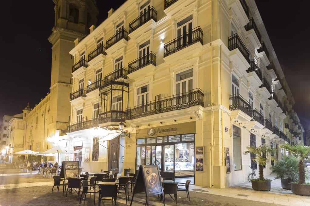 een geel gebouw met tafels en stoelen ervoor bij Hotel San Lorenzo Boutique in Valencia