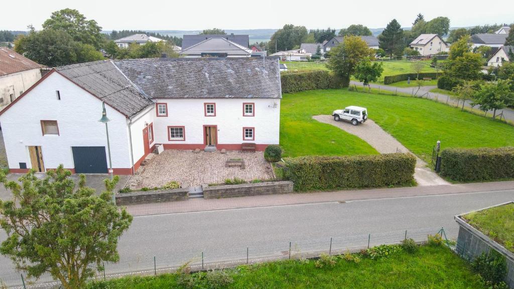 a white house with a car parked in the driveway at Ferienhaus Schneifel in Auw