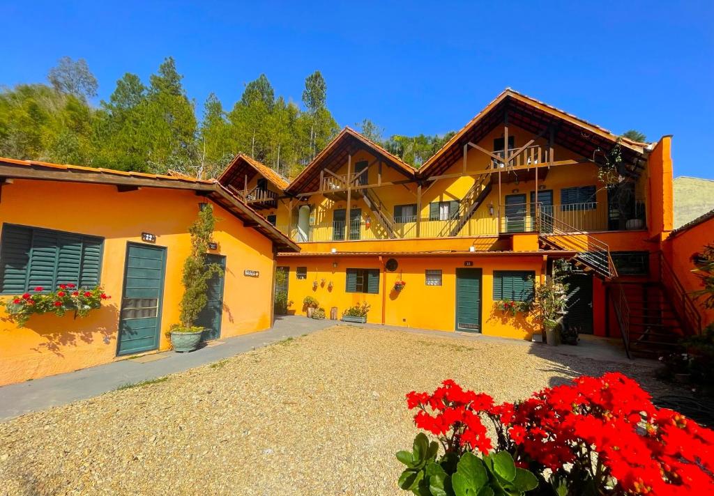 una casa amarilla con flores rojas delante de ella en Pousada Villa Três, en Serra Negra