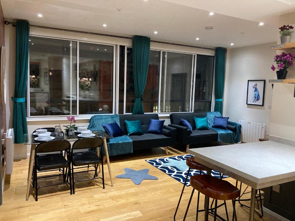 Central Sheffield 3BED 3BATH V Pent-Apartment في شيفيلد: غرفة معيشة مع أريكة زرقاء وطاولة