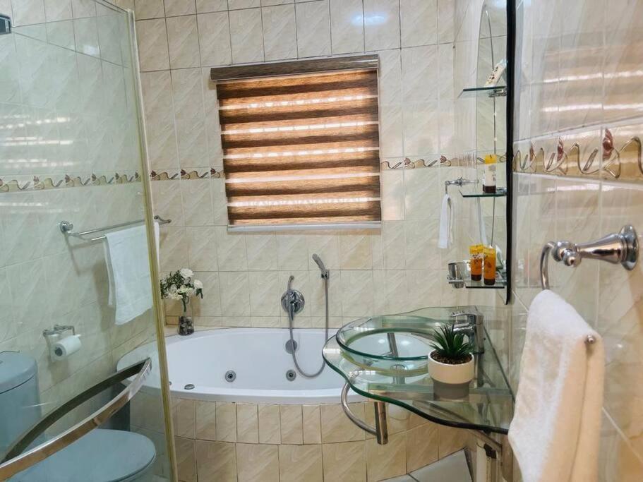 帕拉博魯瓦的住宿－Olebone_C-rane Lodge，一间带玻璃桌、浴缸和淋浴的浴室