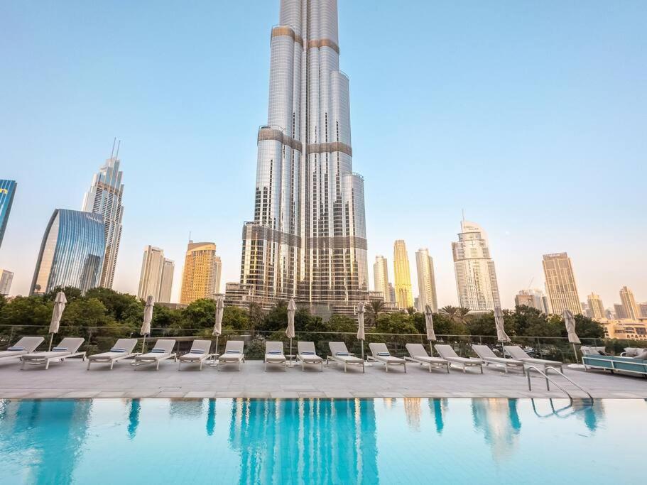 een zwembad met stoelen en een stad op de achtergrond bij Prime Retreats @ Address Residence Opera By Emaar in Dubai