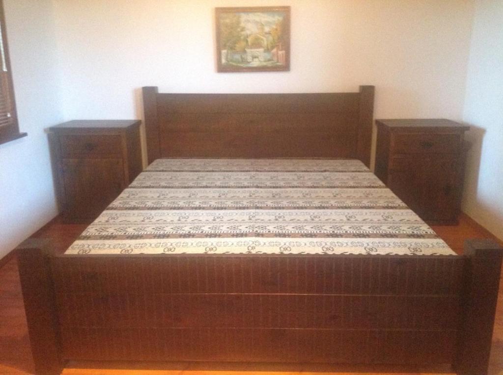 een houten bed in een kamer met 2 nachtkastjes bij Къща за гости Ива 