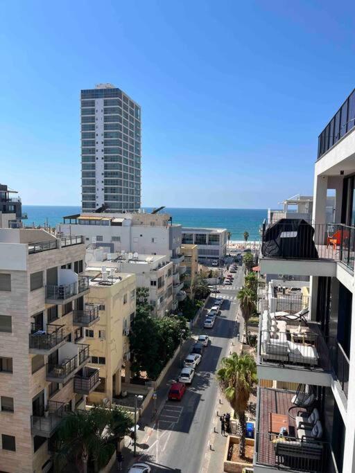 Superbe Penthouse Terrasse avec vue Mer في تل أبيب: اطلالة على شارع المدينة مع المباني والمحيط