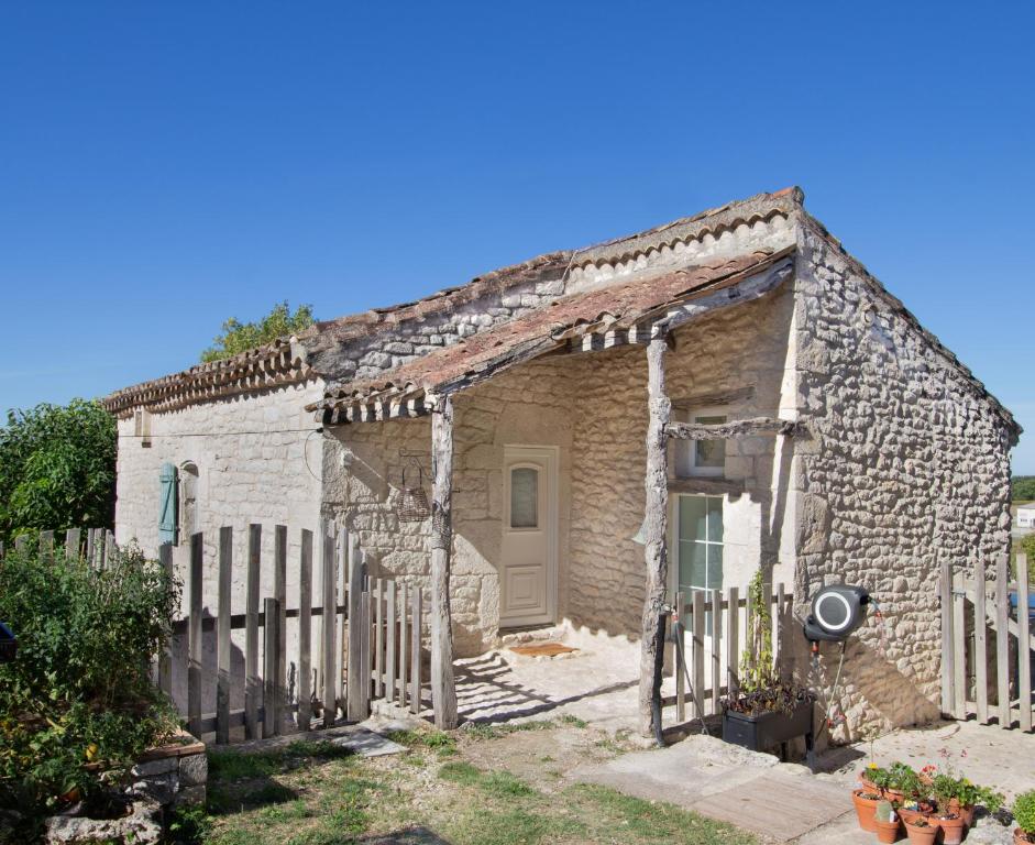 una antigua casa de piedra con una valla de madera en Maisonnette Lotoise, meublé de tourisme 3 étoiles, en Fargues