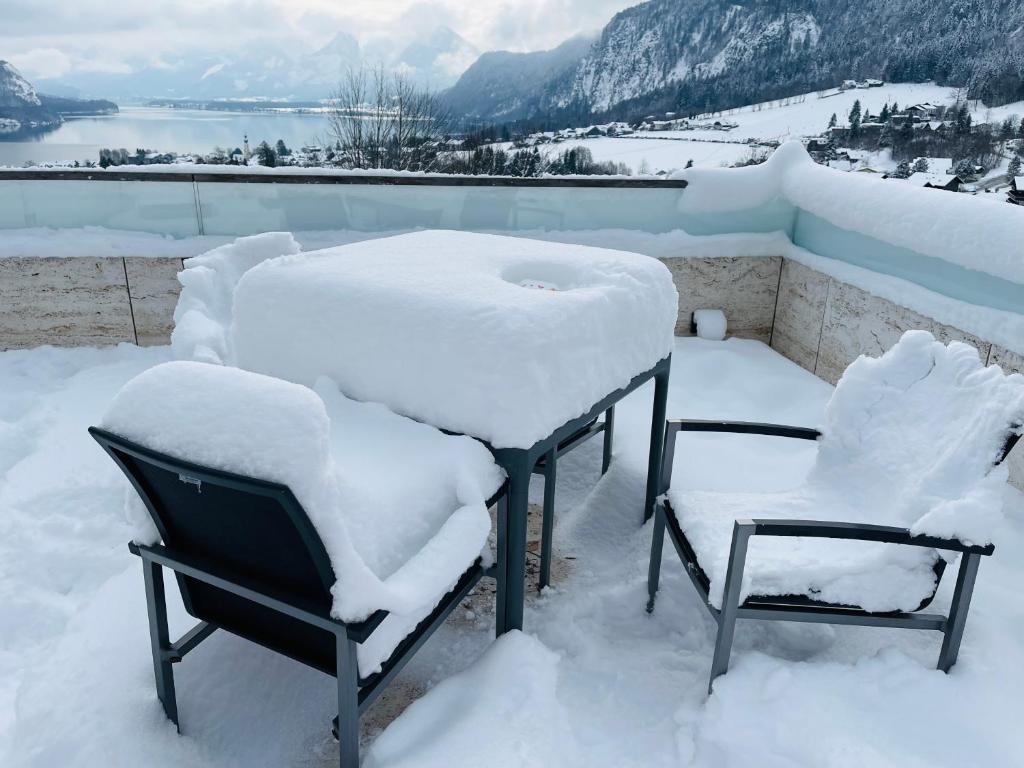 twee stoelen bedekt met sneeuw op een dak bij Modern Living Sankt Gilgen in Sankt Gilgen