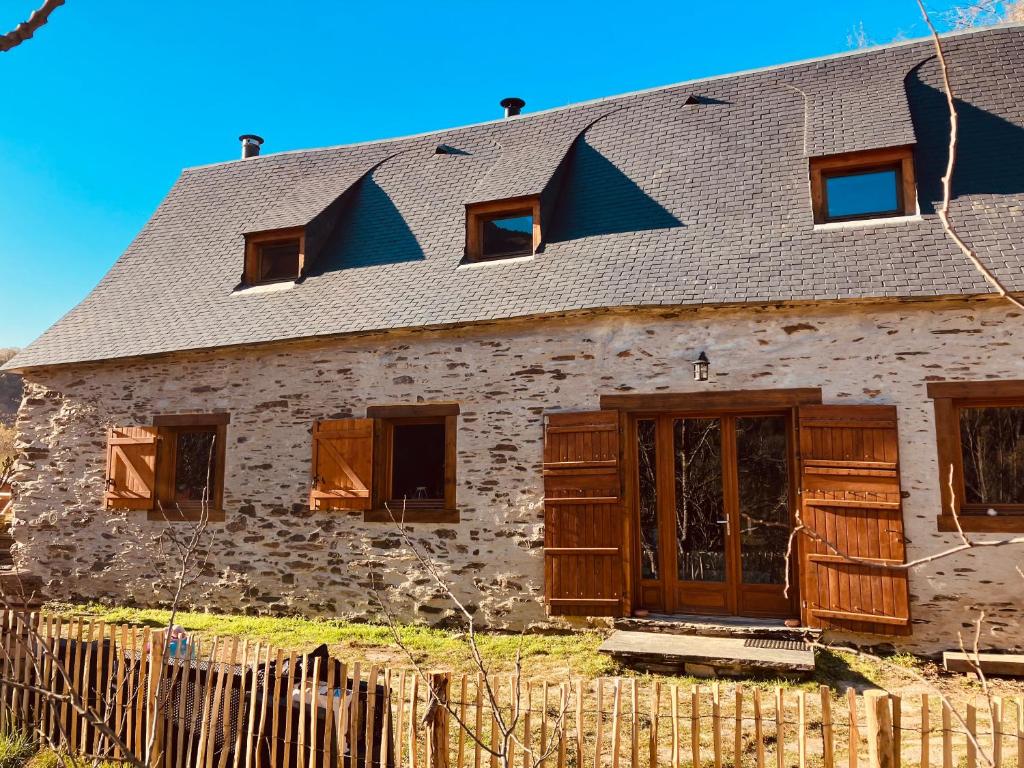 stary kamienny dom z drewnianymi drzwiami i ogrodzeniem w obiekcie Chalet grange w mieście Bareilles