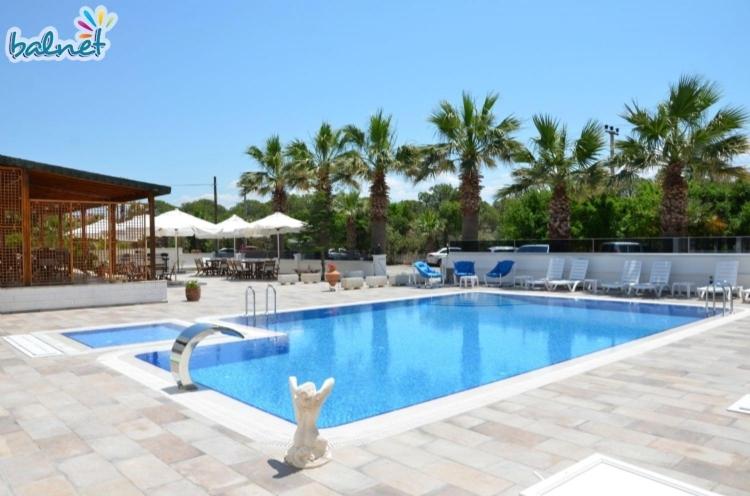 a swimming pool in a resort with palm trees at Tunan Motel in Ayvalık