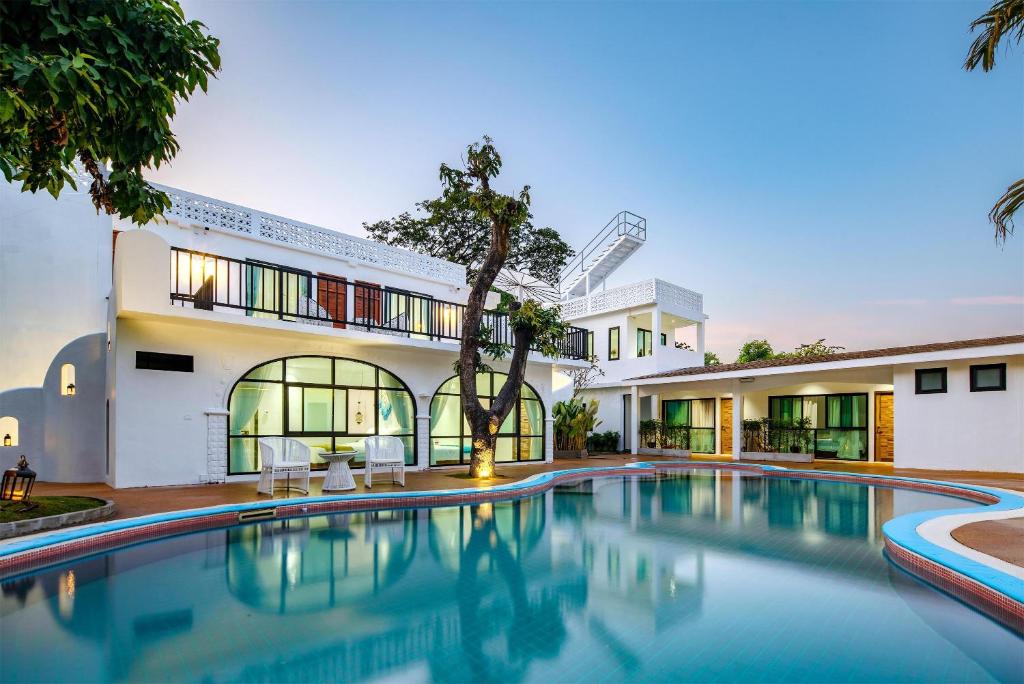 a swimming pool in front of a house at 花语岸·度假酒店(H·Flora Hotel) in Chiang Mai