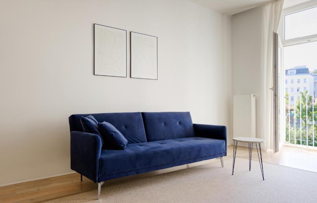 a blue couch in a living room with a window at MINIMALISTIC STUDIO NEAR NASCHMARKT in Vienna