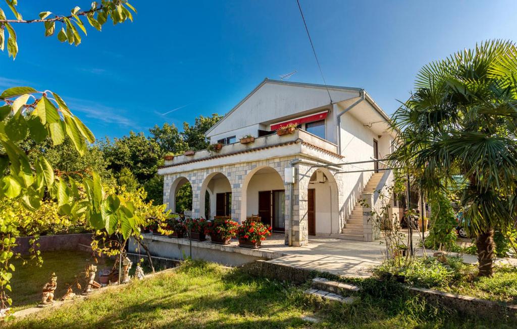 a white house with a palm tree in front of it at Apartman ALEN in Klanice Dobrinj