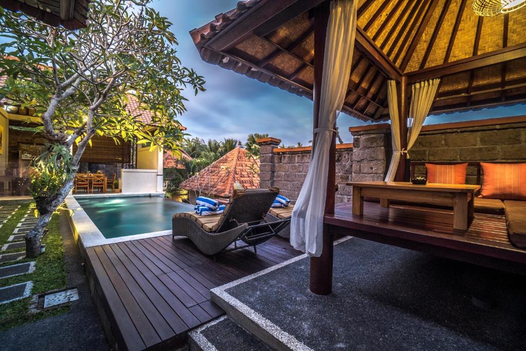 an outdoor patio with a hammock and a swimming pool at Griya Shanti Villas & Spa in Ubud