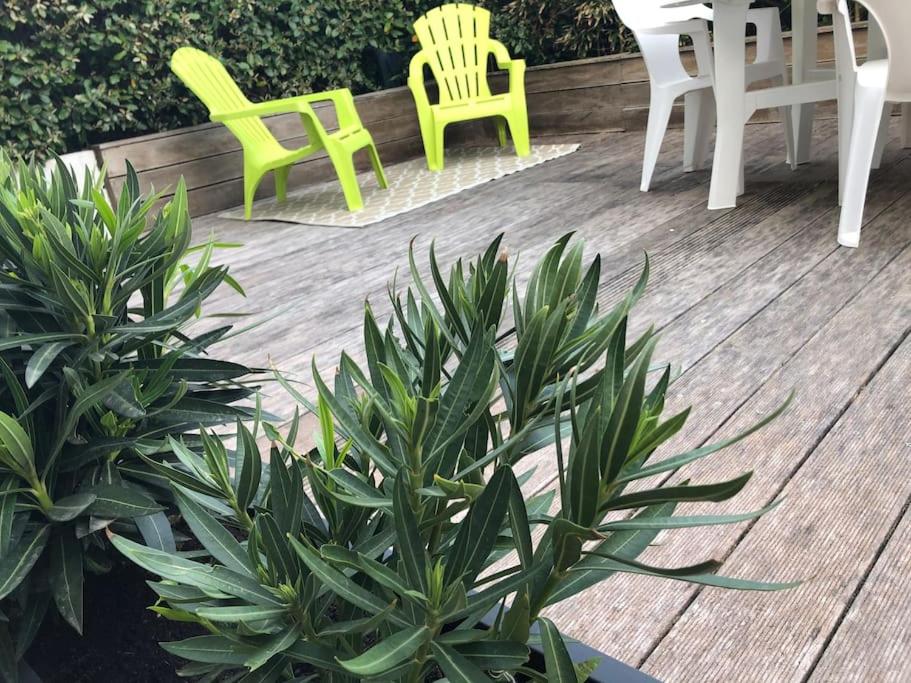 2 chaises et une table avec des chaises sur une terrasse en bois dans l'établissement Flat in a unique location 30 m from the beach with terrace and garden, à Carnac
