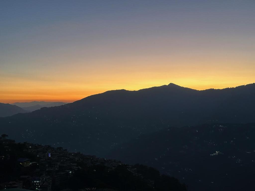 a view of a mountain with the sunset in the background at LASA HOMES in Gangtok