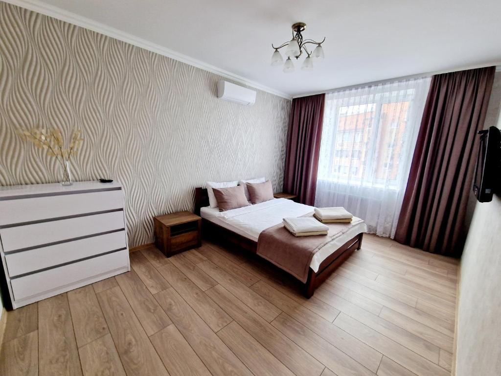 een slaapkamer met een bed, een dressoir en een raam bij Apartament on Chornovola, 40 ЖК "Варварівка" in Loetsk