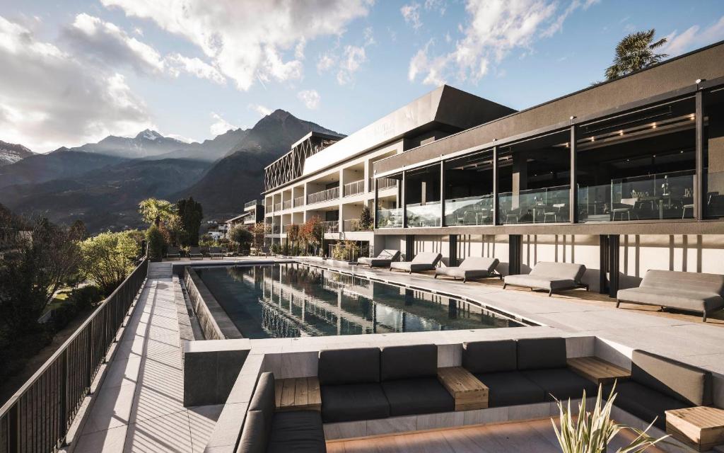 um edifício com uma piscina com montanhas ao fundo em SomVita Suites em Tirolo