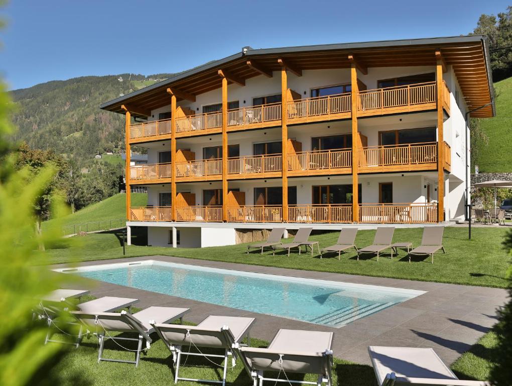 a resort with a swimming pool and chairs and a building at Natur Residence Kaiser Hans in Schenna