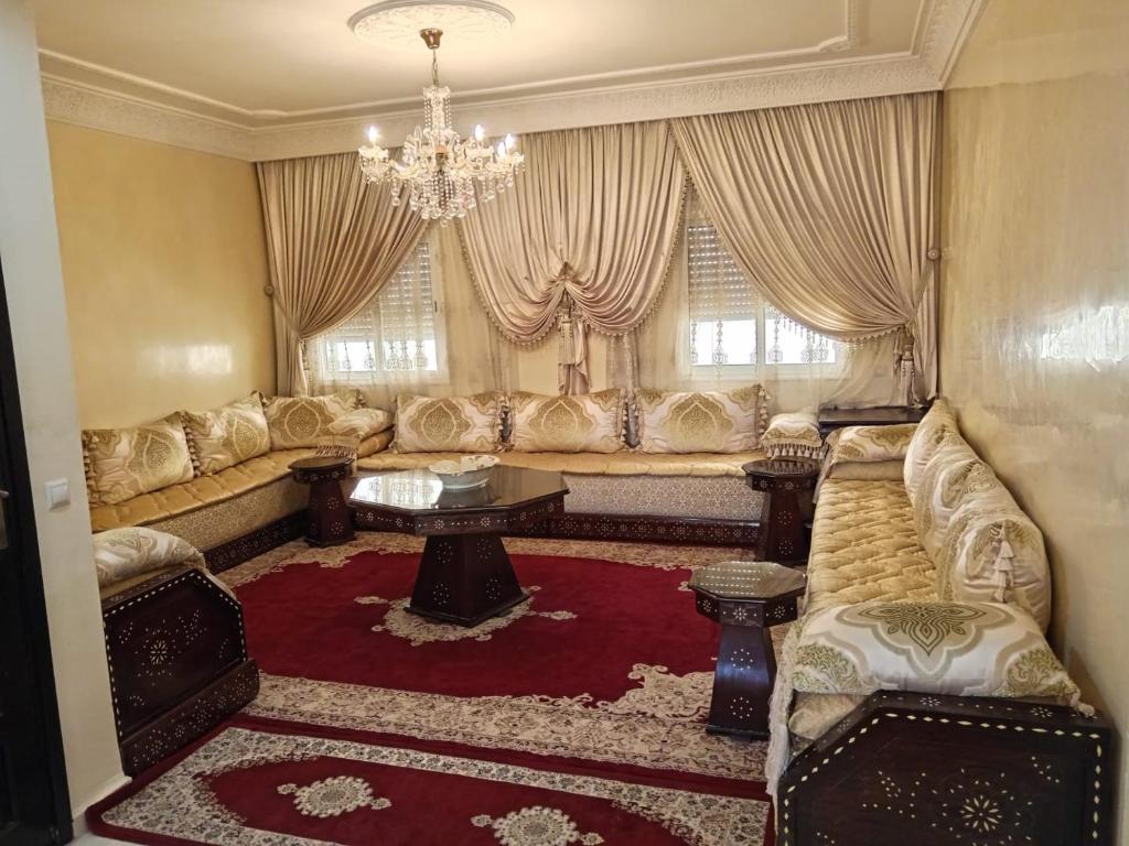 een woonkamer met banken en een kroonluchter bij Appartement la vallée in Oulad Akkou