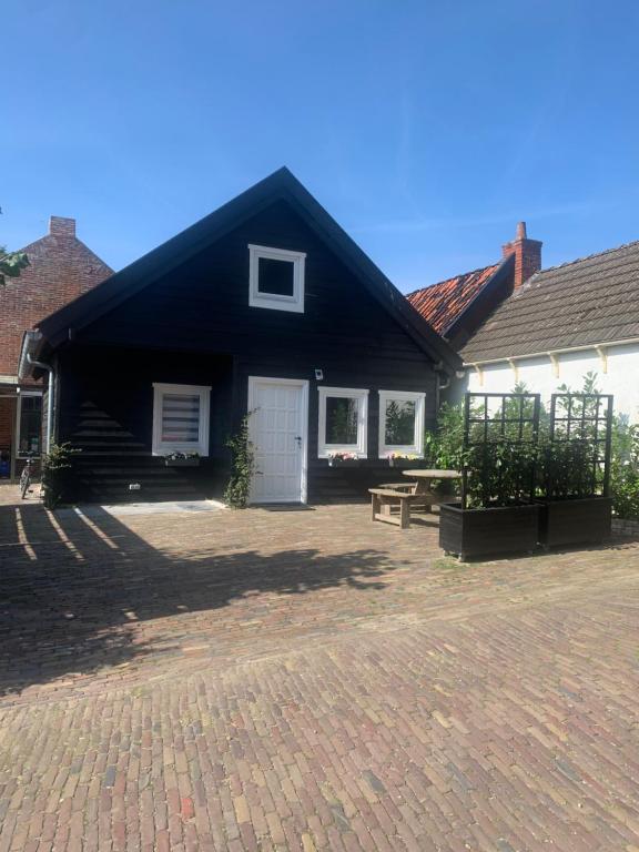 una casa en blanco y negro con un banco delante en Het molenhuisje en Winsum