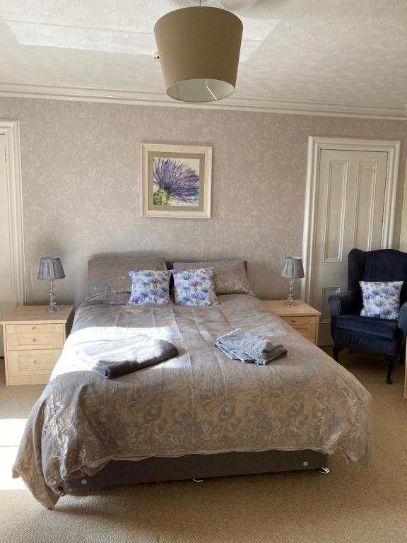 - une chambre avec un grand lit et une chaise bleue dans l'établissement 47 High Street, à Alness