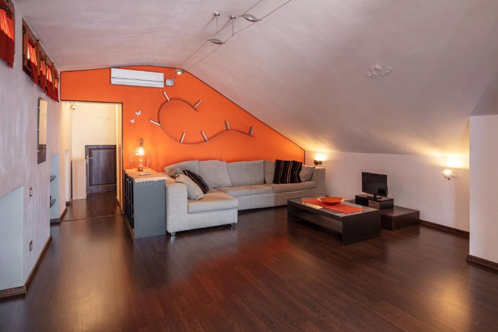 a living room with a couch and an orange wall at Mansarda vista mare in Massa Marittima