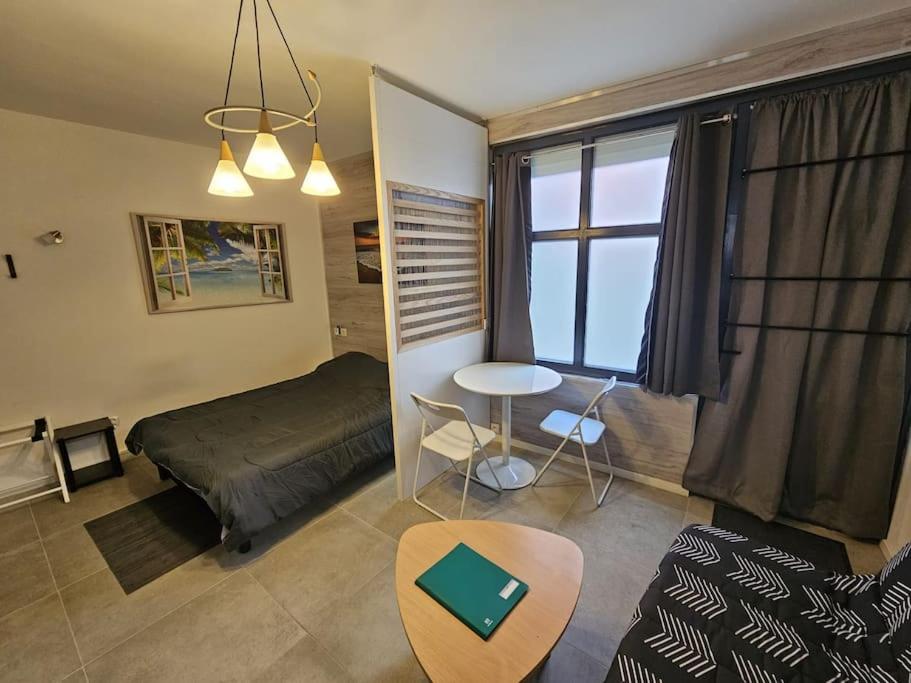 Schlafzimmer mit einem Bett, einem Tisch und einem Fenster in der Unterkunft Studio bien équipé proche mer in Montpellier