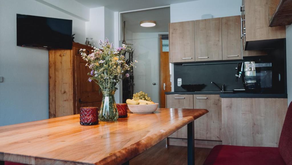 uma cozinha com uma mesa de madeira com um vaso de flores em Appartement Alpenrauschen em Planneralm