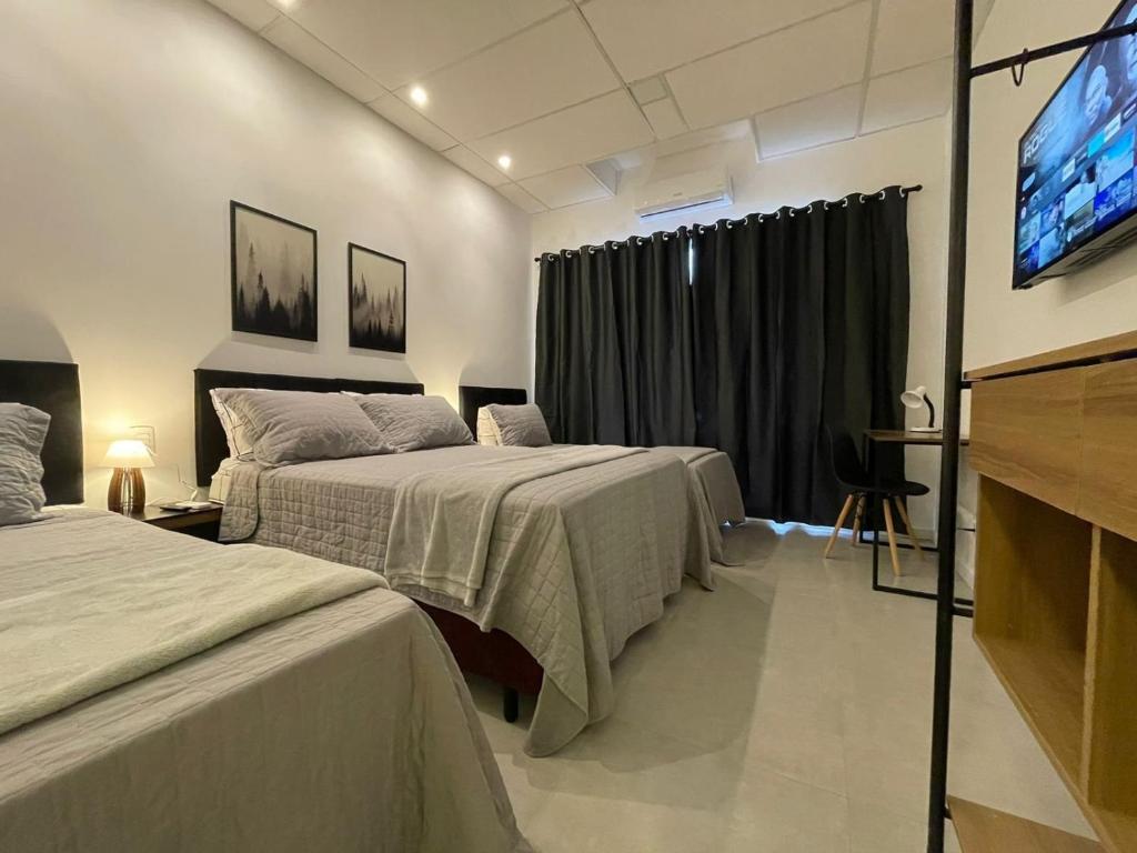a hotel room with two beds and a flat screen tv at VILLA BILAC 03 - Studio próximo à Vila Germânica in Blumenau