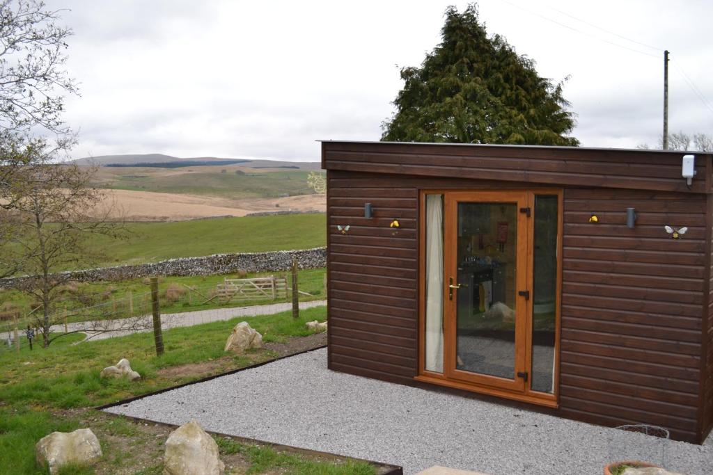 ein kleines Holzhaus mit Glastür in der Unterkunft The Hive at Ashes Farm in Settle