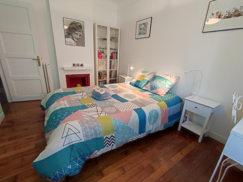 - une chambre avec un lit et une couette colorée dans l'établissement Grand appartement Athis Mons proche Paris, à Athis-Mons
