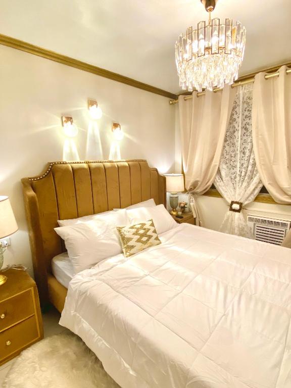 a bedroom with a large white bed with a chandelier at RK Maisson Roiyale Pasig in Manila