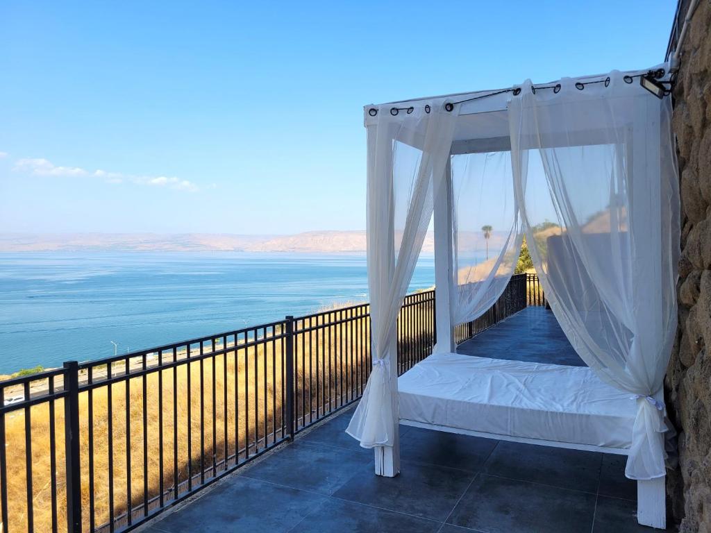 a bed on a balcony with a view of the ocean at Yalarent Europe apartments- Luxury big apartmens with lake view in Tiberias