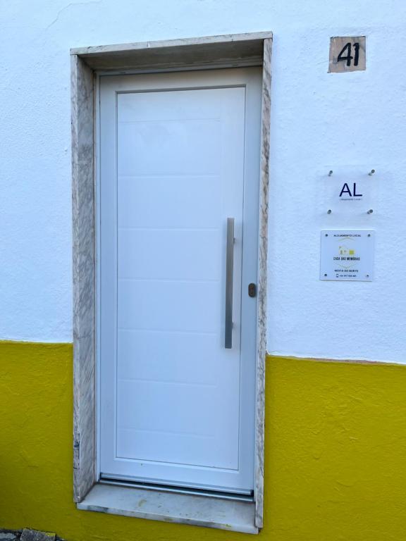 una porta bianca su un edificio giallo e bianco di Casa das Memórias 