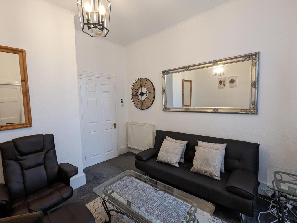 a living room with a black couch and a mirror at The Summit West End- Elegant Apartment with Free Parking in Prime Location in Aberdeen