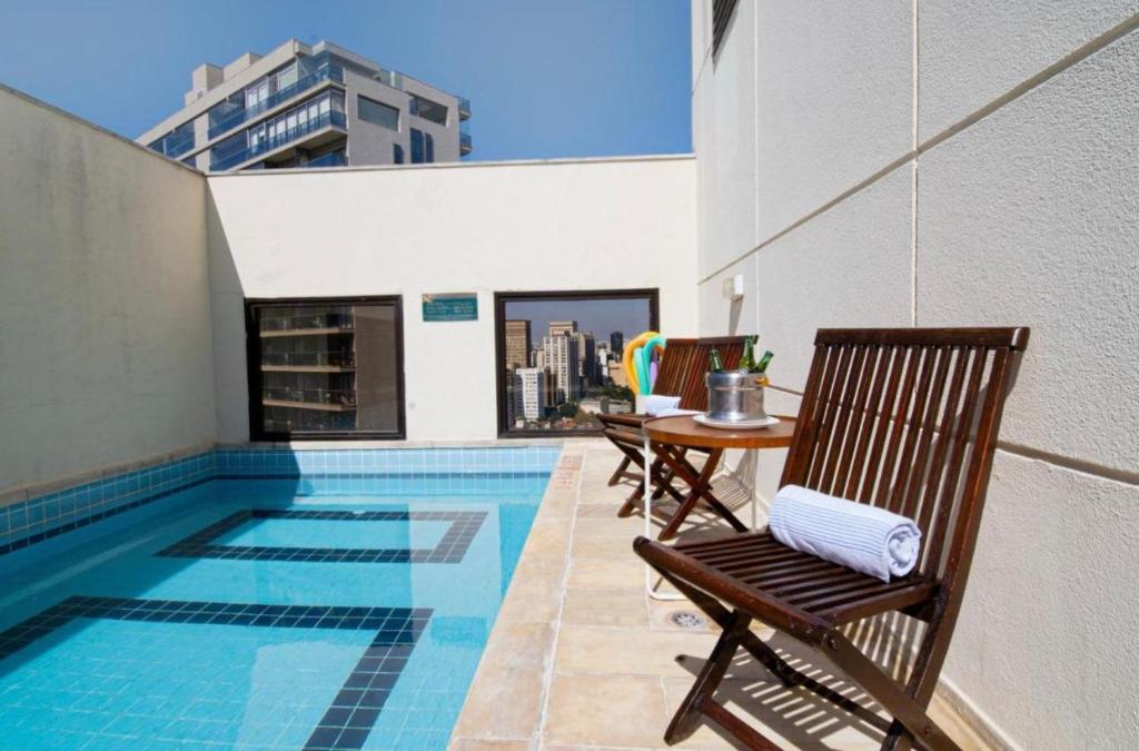 a pool with chairs and a table next to a building at Studio Living Faria Lima in Sao Paulo