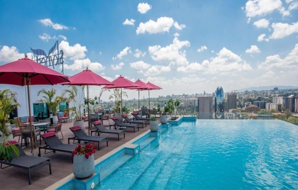 a pool with chairs and umbrellas on top of a building at Luxury Skynest with Gym and Pool in Westlands in Nairobi
