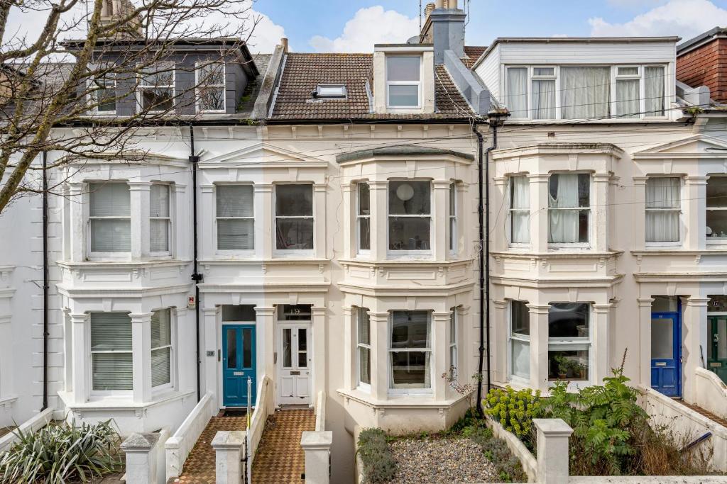 Une grande maison blanche avec une porte bleue dans l'établissement Hove garden flat, pet friendly, à Brighton et Hove