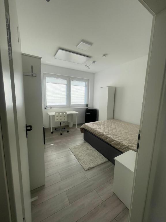 een slaapkamer met een bed, een bureau en een raam bij Hostel Kornwestheim in Kornwestheim