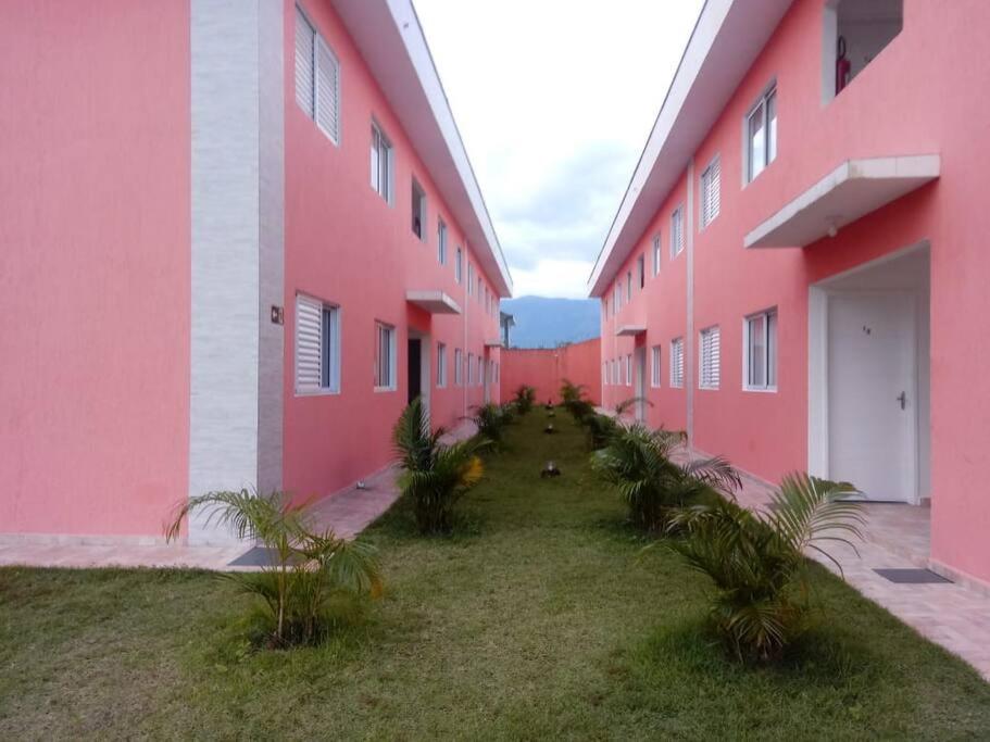 a row of pink buildings with palm trees between them at Apartamento Em Balneário Mogiano in Bertioga