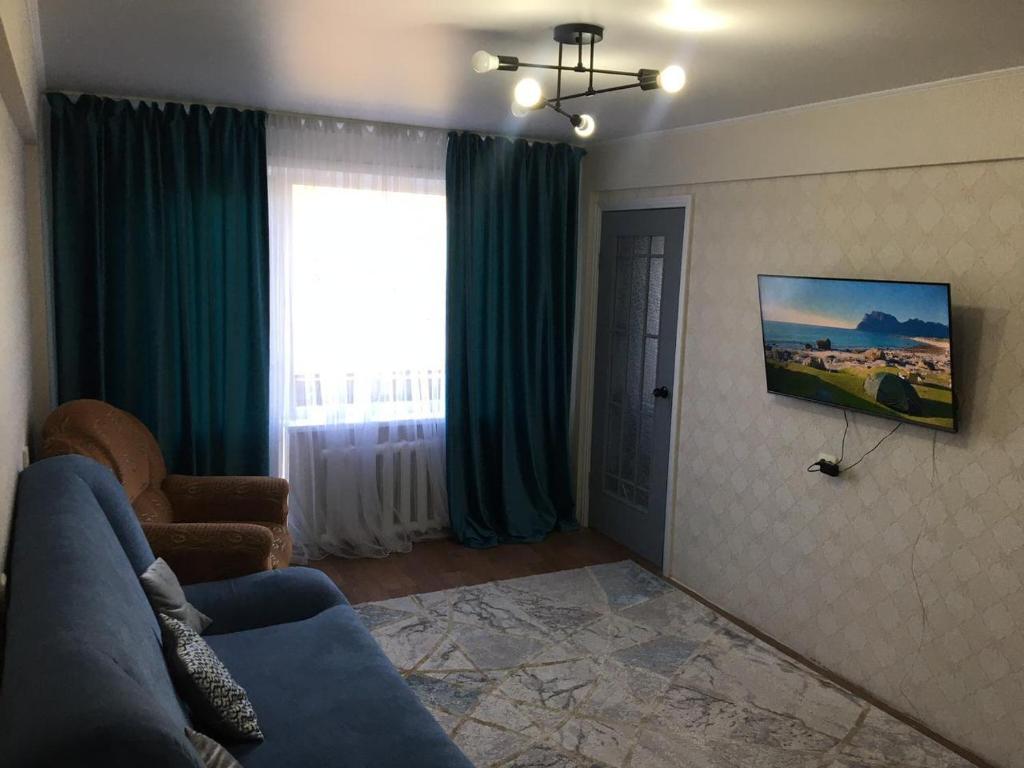 ein Wohnzimmer mit einem blauen Sofa und einem Fenster in der Unterkunft Lux Home на Новаторов in Öskemen