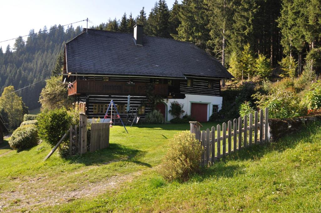 a house on a hill with a wooden fence at Altes Bauernhaus in Gnesau