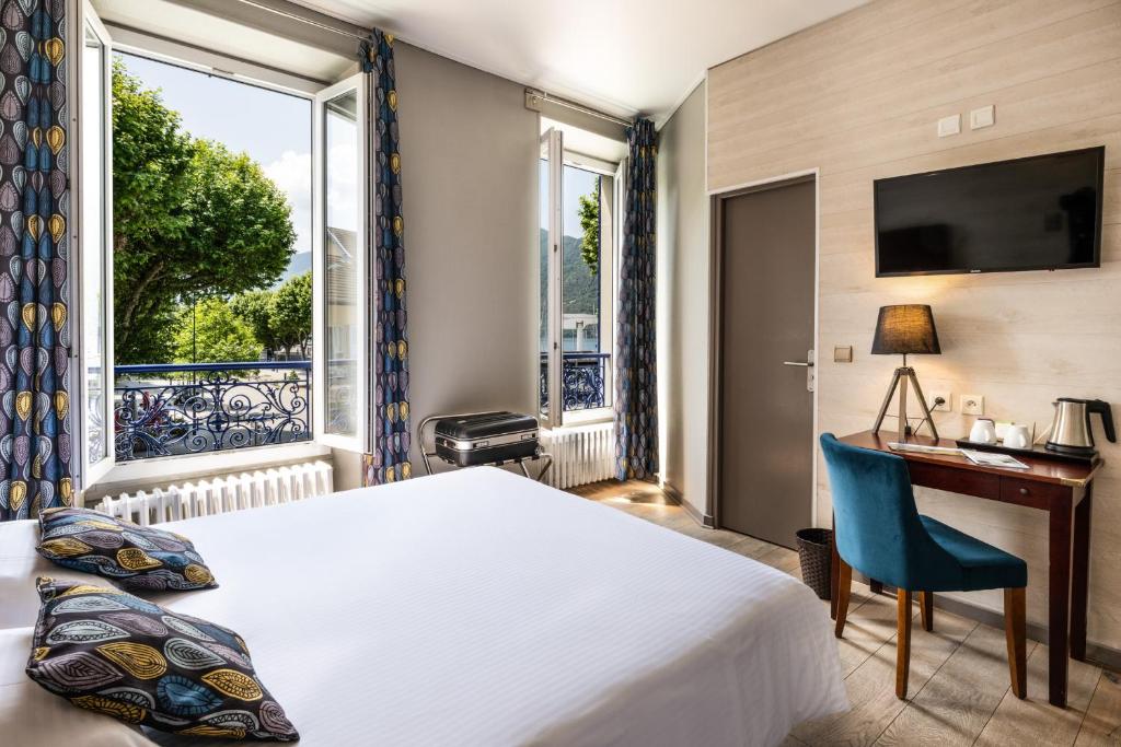 a hotel room with a bed and a desk and a window at Hotel Beau Rivage in Aix-les-Bains