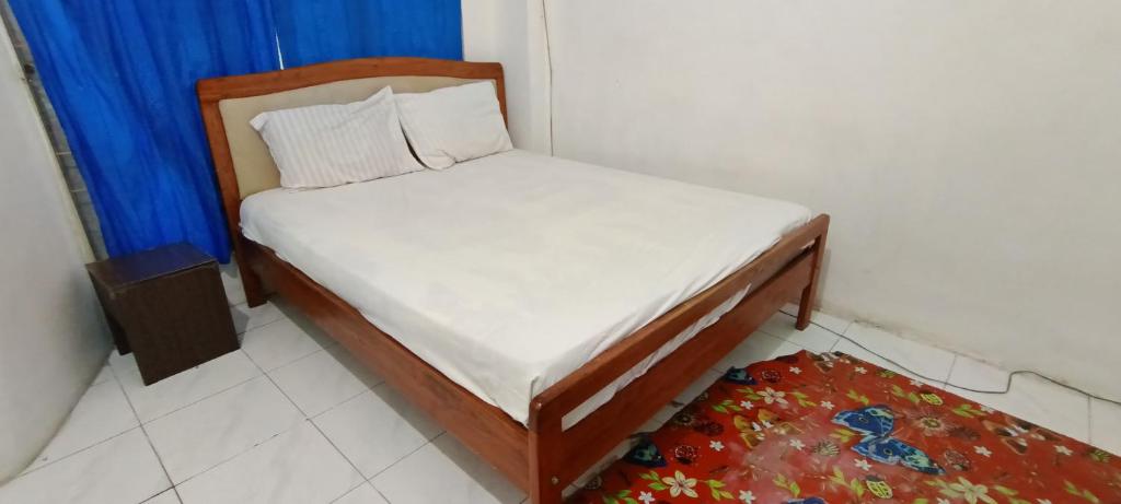 ein kleines Bett in einem Zimmer mit einem blauen Vorhang in der Unterkunft OYO 93122 Pondok Puti Sartika Syariah in Banjarmasin