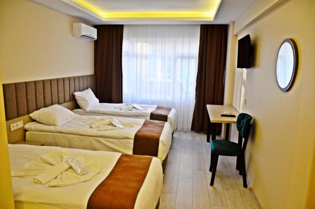 a hotel room with two beds and a desk at Yesilirmak Aparts Hotel in Istanbul
