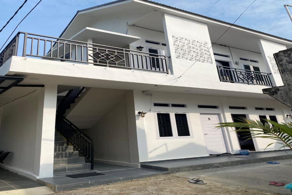 a white house with a balcony at OYO 93126 Nrc White House in Duri