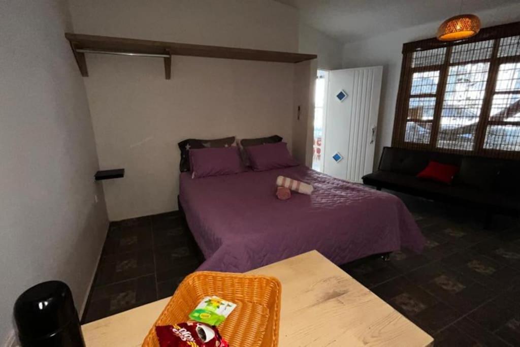 um quarto com uma cama roxa e um sofá em Apartamento centro Santa Marta em Santa Marta