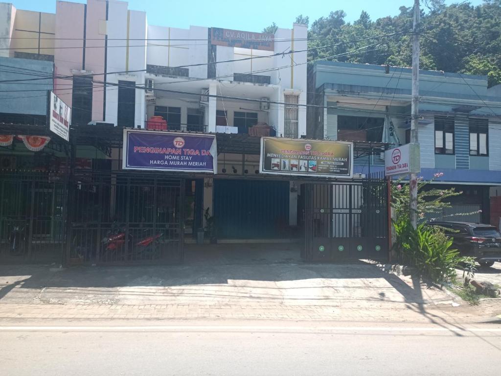 ein Gebäude mit Schildern an der Straßenseite in der Unterkunft OYO 93117 Penginapan Tiga Dara in Jayapura